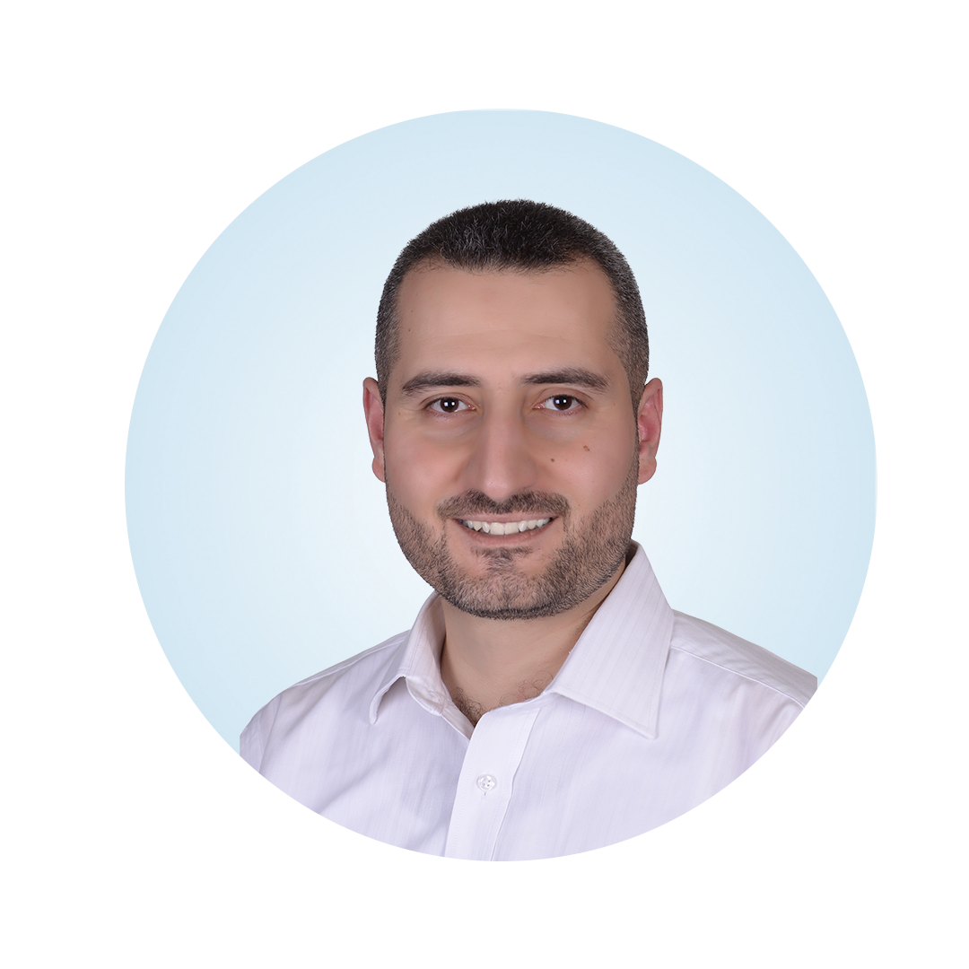 Head-and-shoulders portrait of a smiling man with short dark hair and a trimmed beard, wearing a white collared shirt, against a light blue circular background.